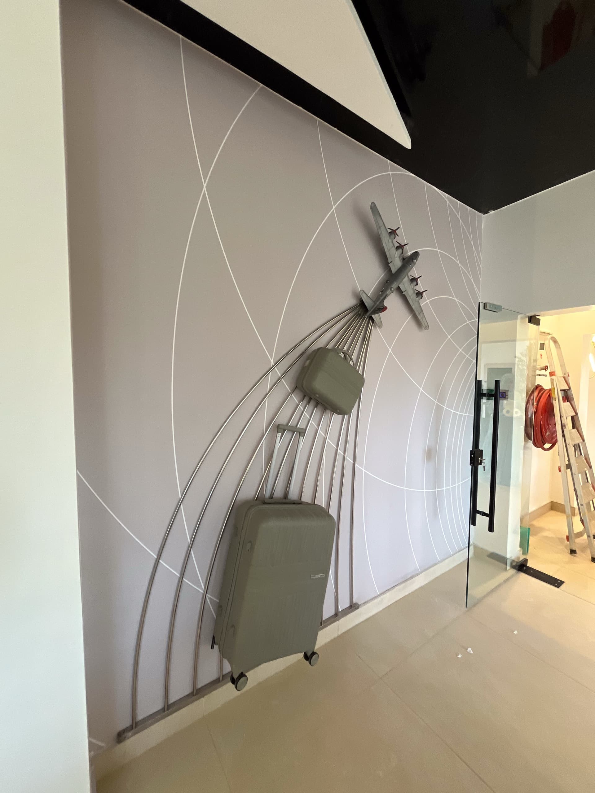 Bespoke aviation feature wall — model aircraft and trailing luggage sculpture against radar-line graphics