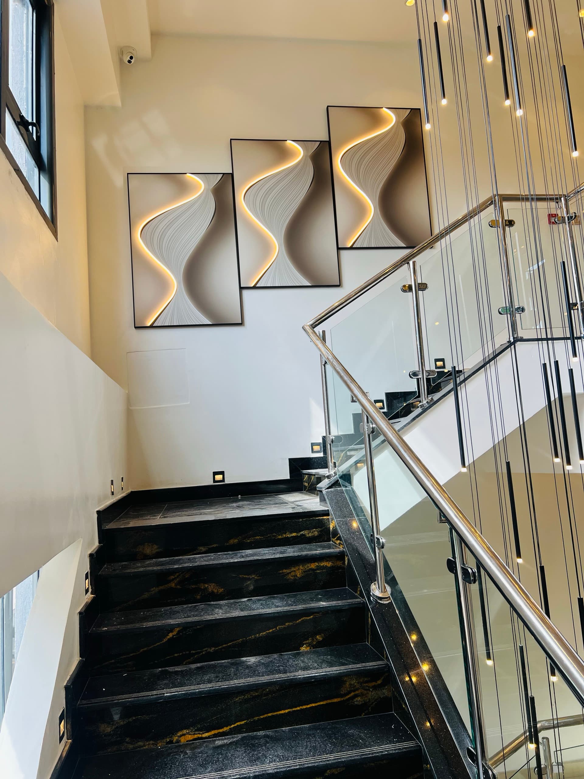 Black Marquina-style marble staircase with chrome balustrade and aviation wave artwork