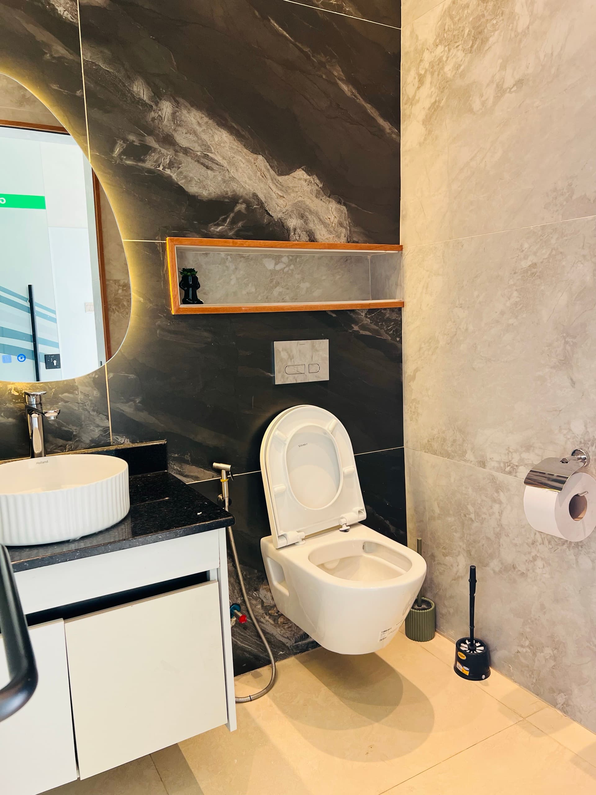 Executive washroom — black marble wall, round backlit mirror and vessel sink